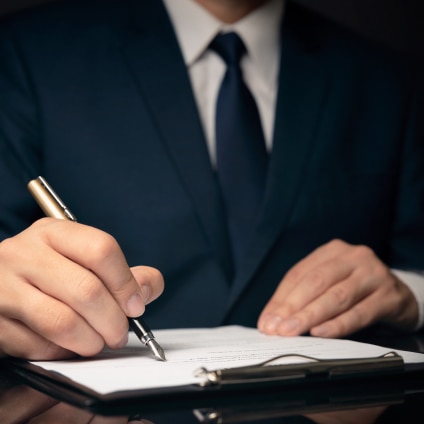 A pair of hands are seen putting pen to paper.