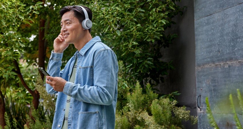 Man wearing headset collaborates outside on the go with Webex on his mobile phone.