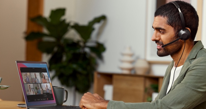 Person in a headset video conferences with several other people from Webex on a laptop.