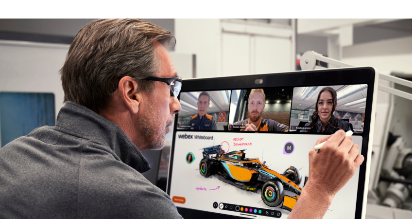 A team member at a desk uses a digital whiteboard to work on a car design during a video meeting with 3 others.