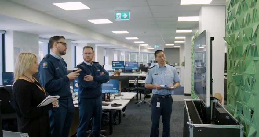 Four colleagues stand in the office and converse together.