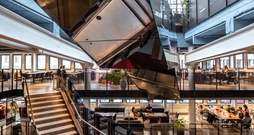 The Rebel building. The photo shows people connecting in various meeting areas with couches, tables, etc. on multiple floors.