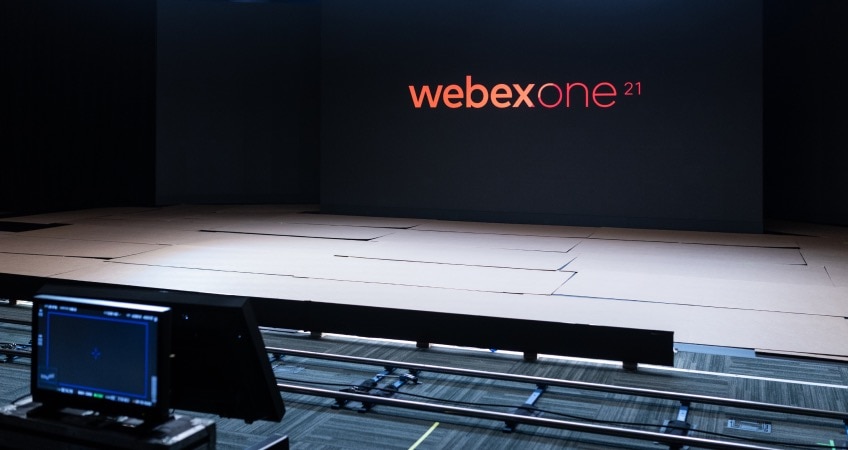 A large stage with a black backdrop that has the words WebexOne 21 displayed on it in orange and red font.