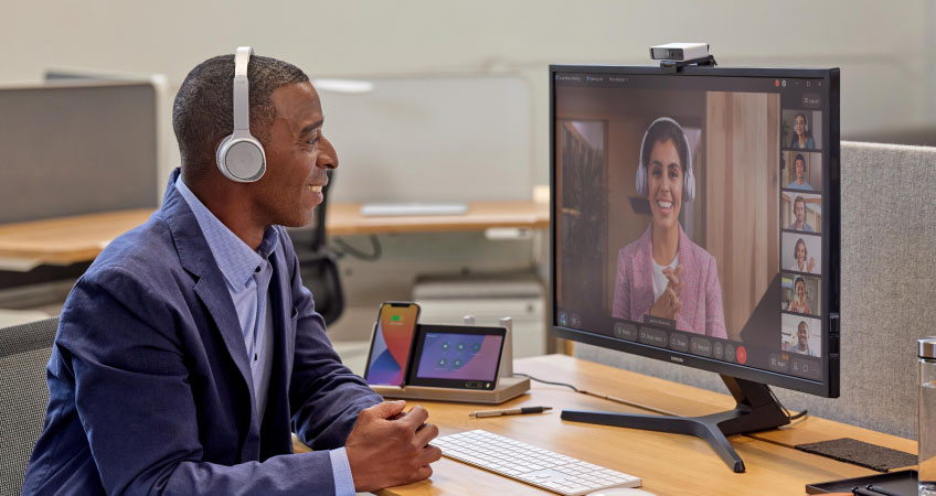 An individual in a blue suit and a headset collaborates with colleagues via a video conference.