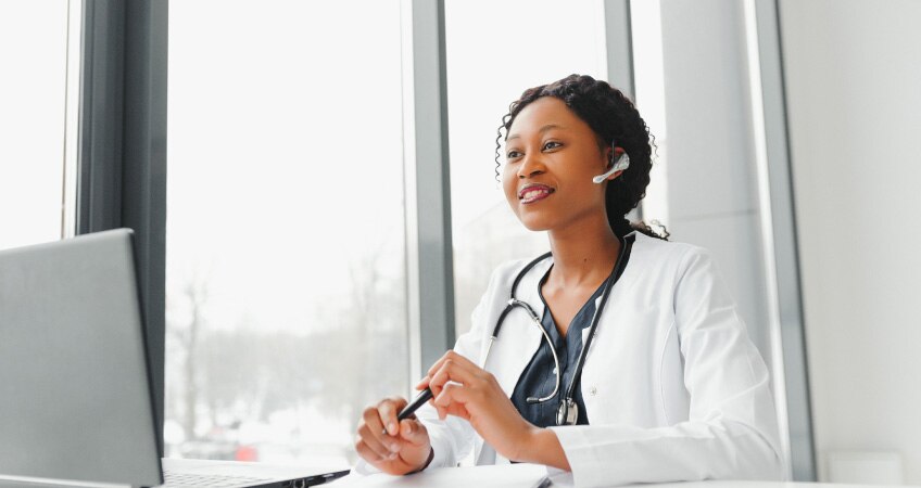 A medical professional in a white coat conducts a telehealth appointment.