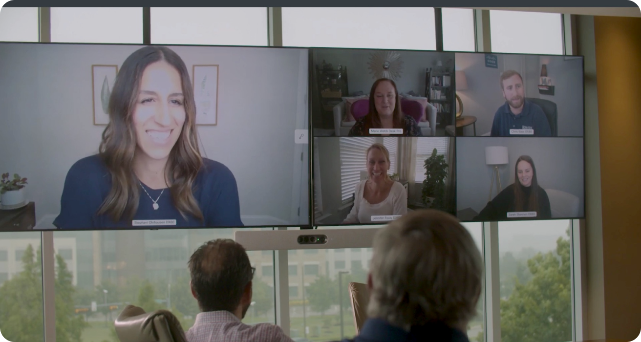 The team collaborates via a video meeting, with some people joining from a conference room and others from other locations.