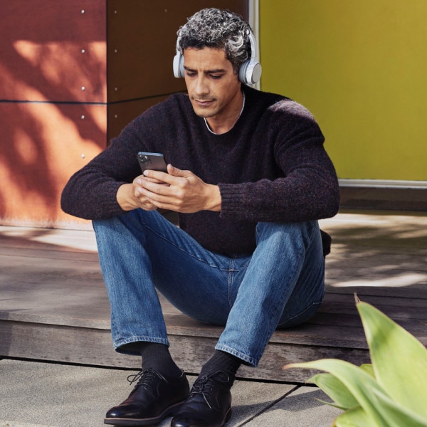 Person in a headset makes a call via Webex on a mobile phone while sitting outside.
