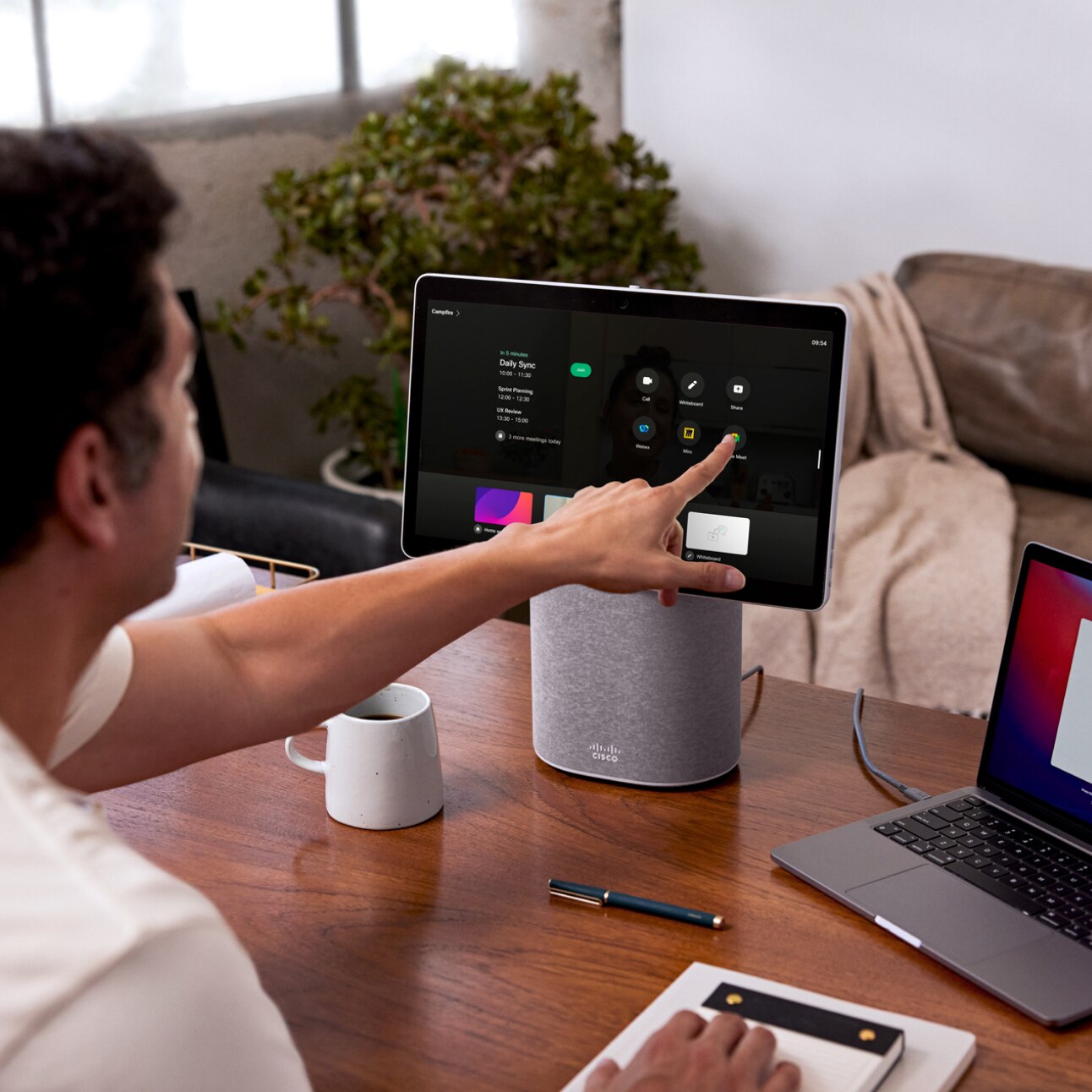 ノートパソコンの横にある Cisco Desk Mini のタッチスクリーンを使ってリモートワークする人。