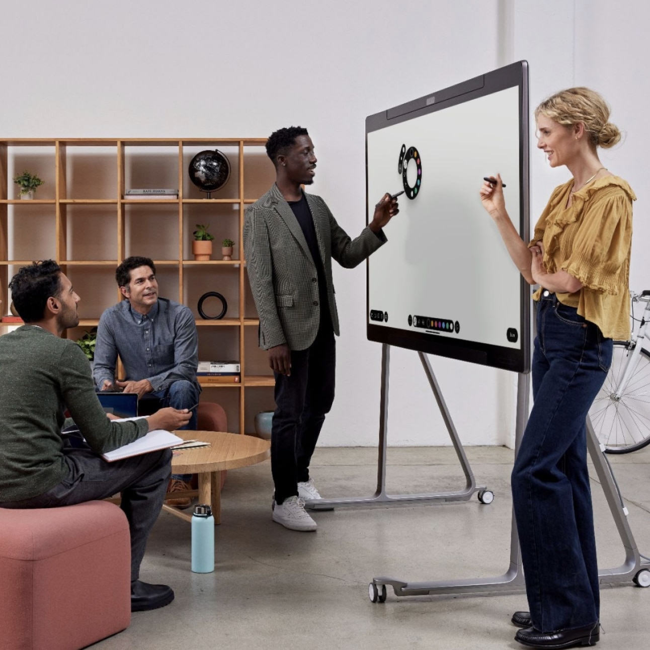 Team of four people in an office using the Cisco Board pro collaboration device for digital whiteboarding