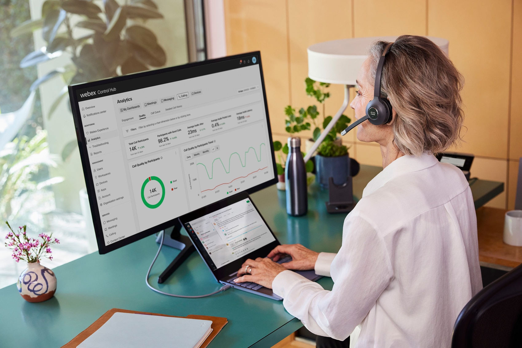 A smiling person video conferences with a colleague from a home office on a Webex Desk Mini.