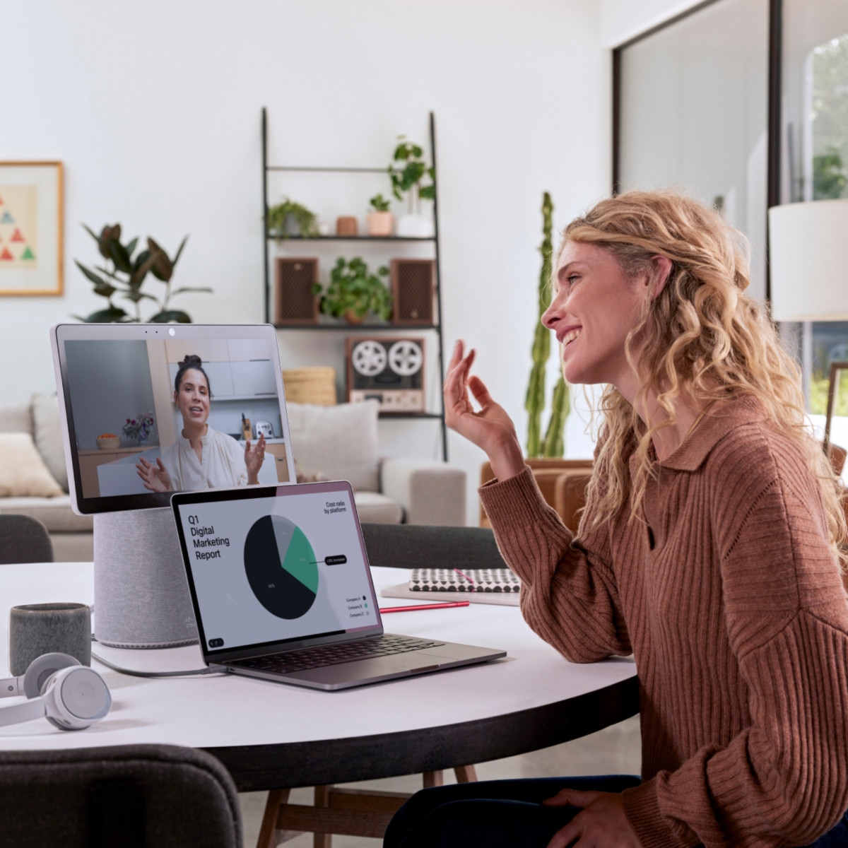 A smiling person video conferences with a colleague from a home office on a Webex Desk Mini.