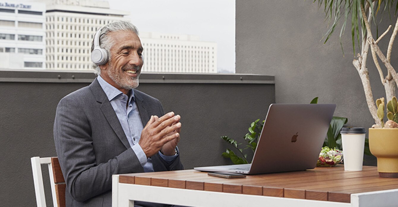 A person is engaged in a meeting using a laptop and headphones.