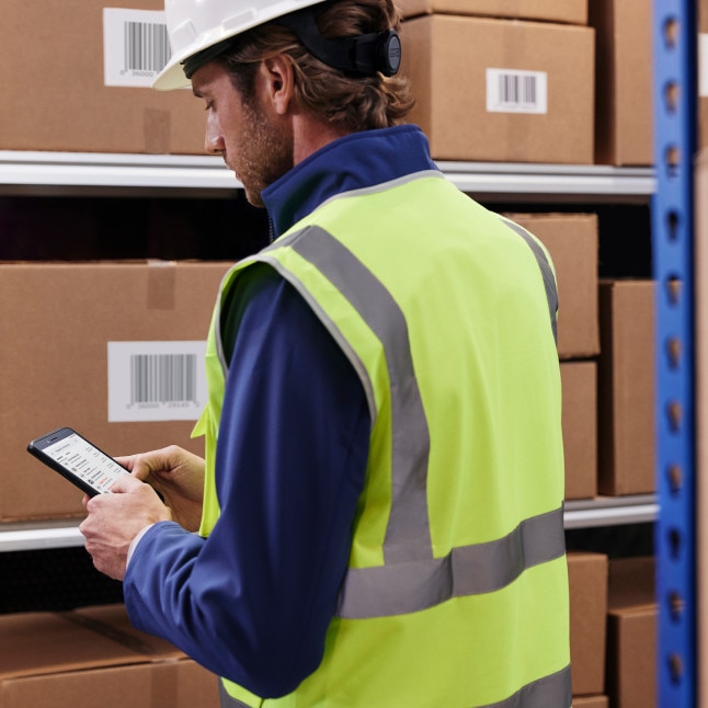 person in what looks like a warehouse/stockroom using mobile device to work away from desk