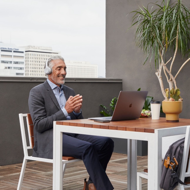 person outside having video call on laptop, looking relaxed and productive