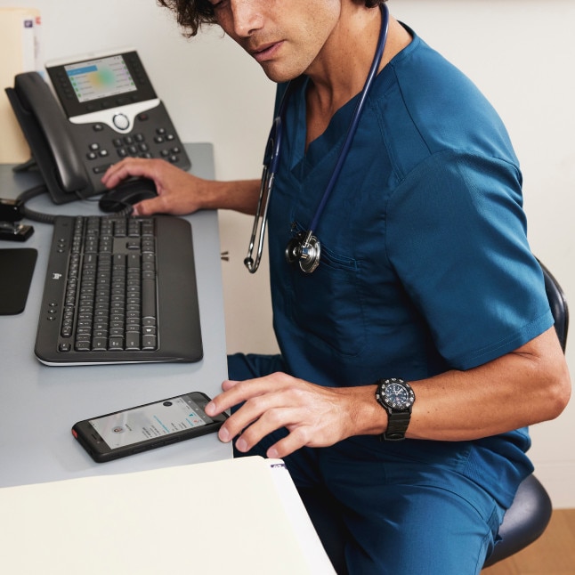 medical worker looking busy at a desktop with phone, mobile phone, keyboard, and mouse