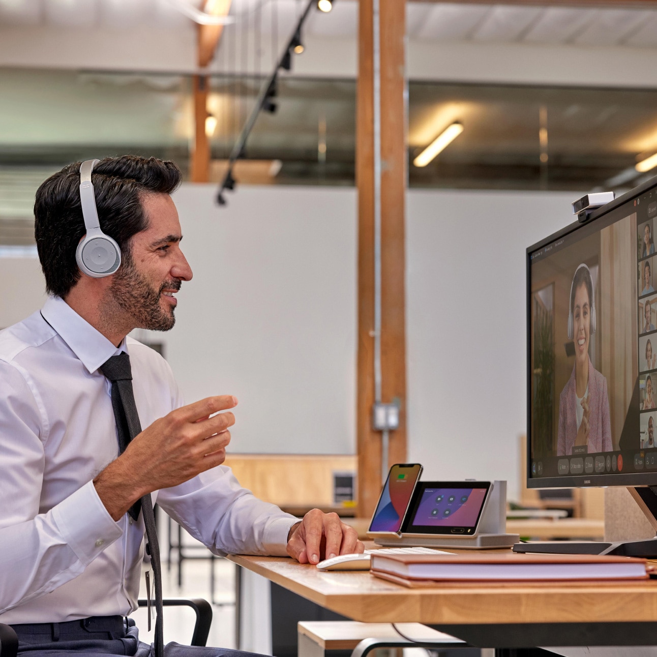 A person wearing headphones in an office meets with a teammate on Webex Meetings.