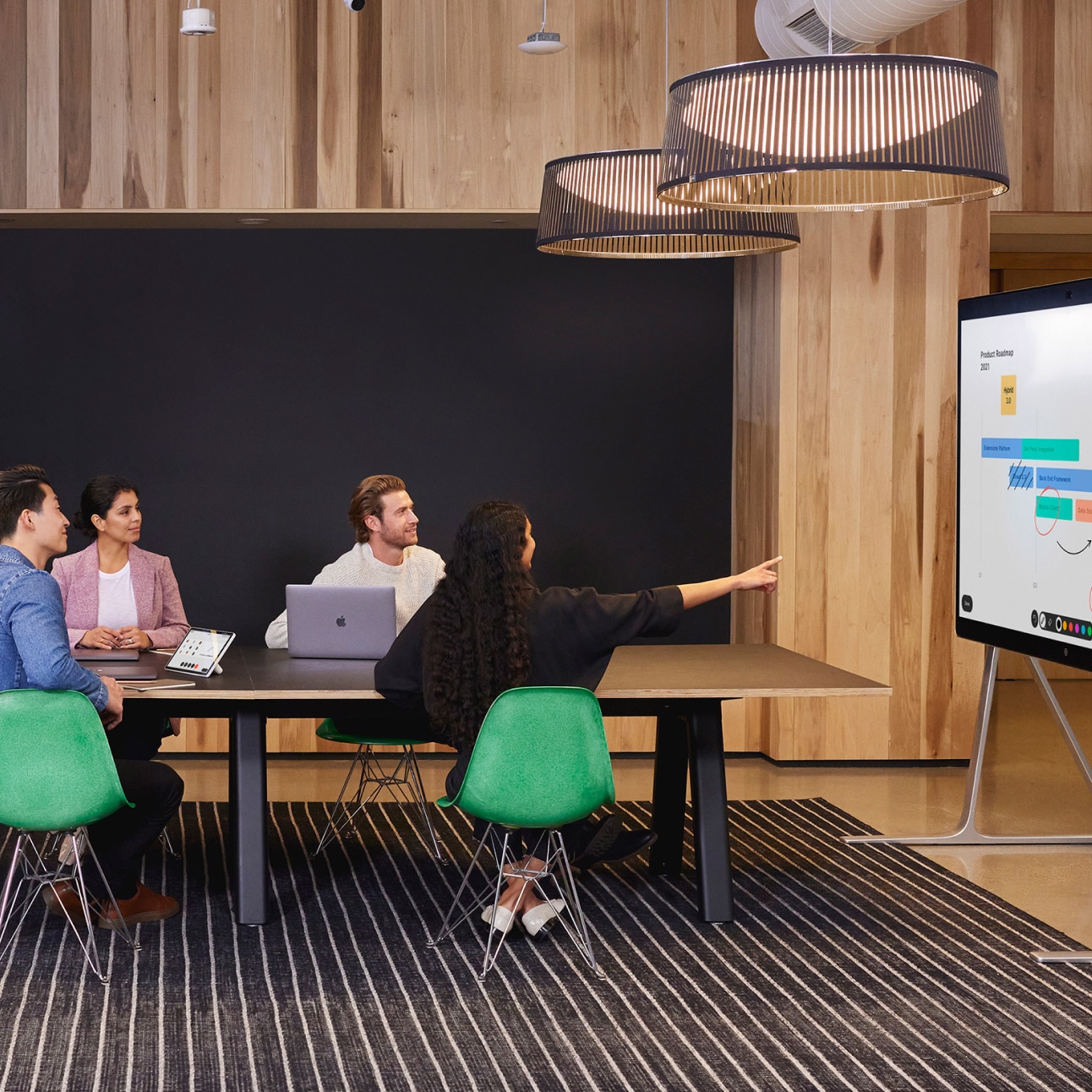 A person presents to colleagues in a conference room using the Webex Board Pro.