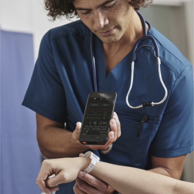 A medical professional in scrubs and a stethoscope utilizes a mobile phone.