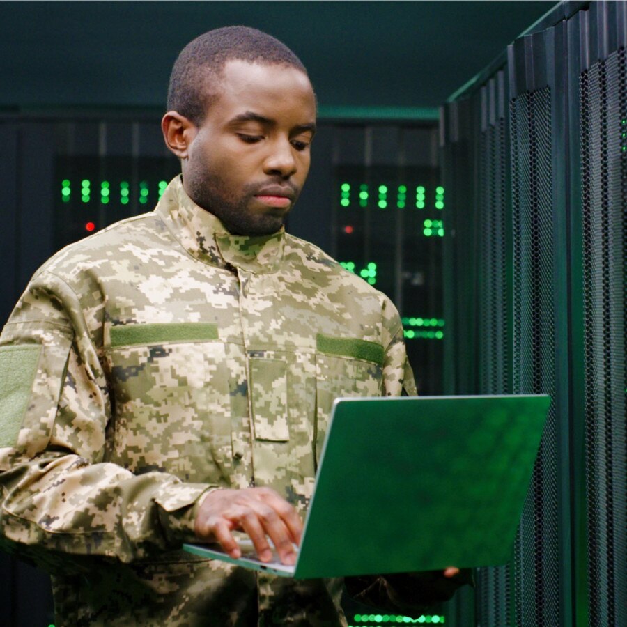 A soldier in uniform types on a laptop.