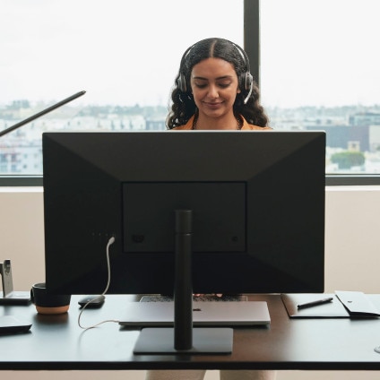 Person wearing a headset works at a desk in an office building.