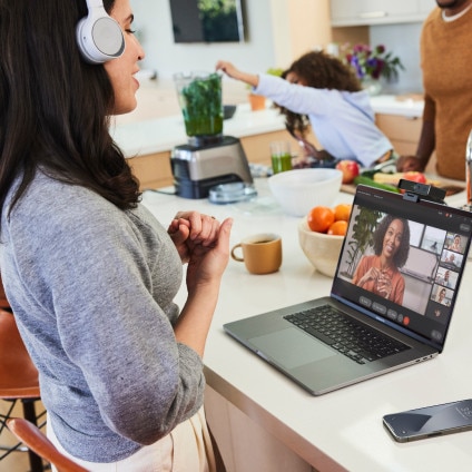 While working from home, a person collaborates with several colleagues via a video meeting on her laptop in the kitchen.