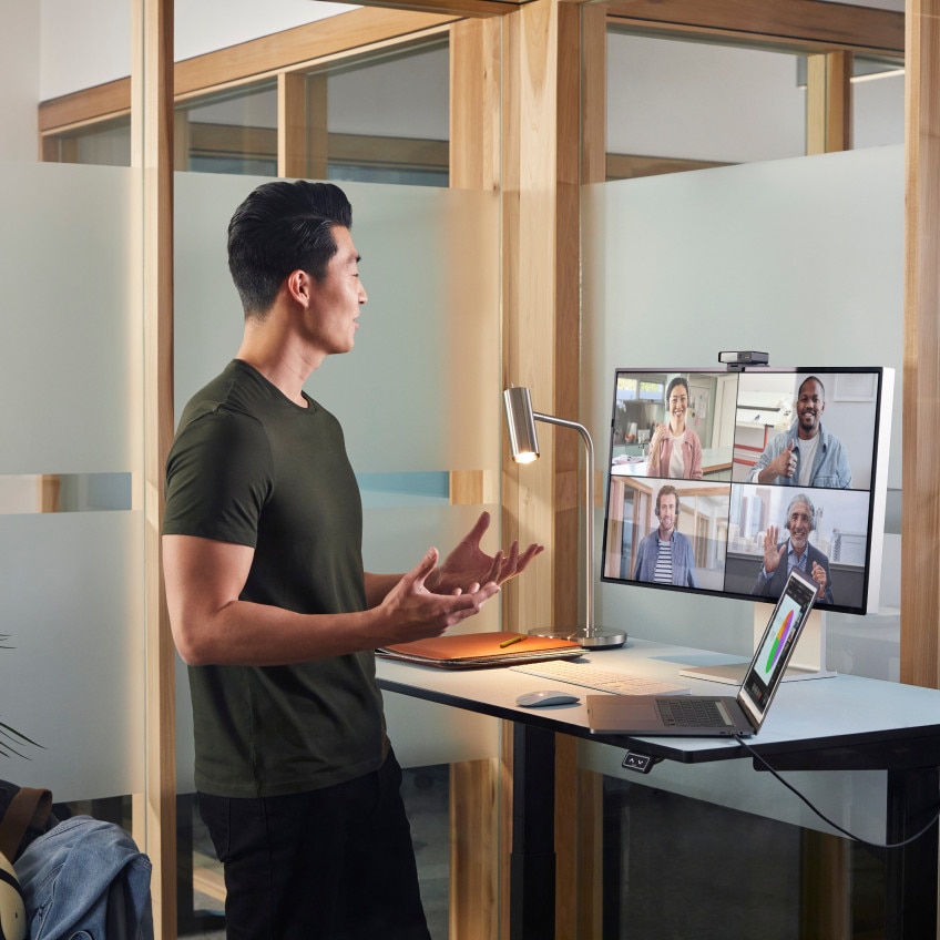 A person at a standing desk video conferences with four colleagues via Webex Meetings.