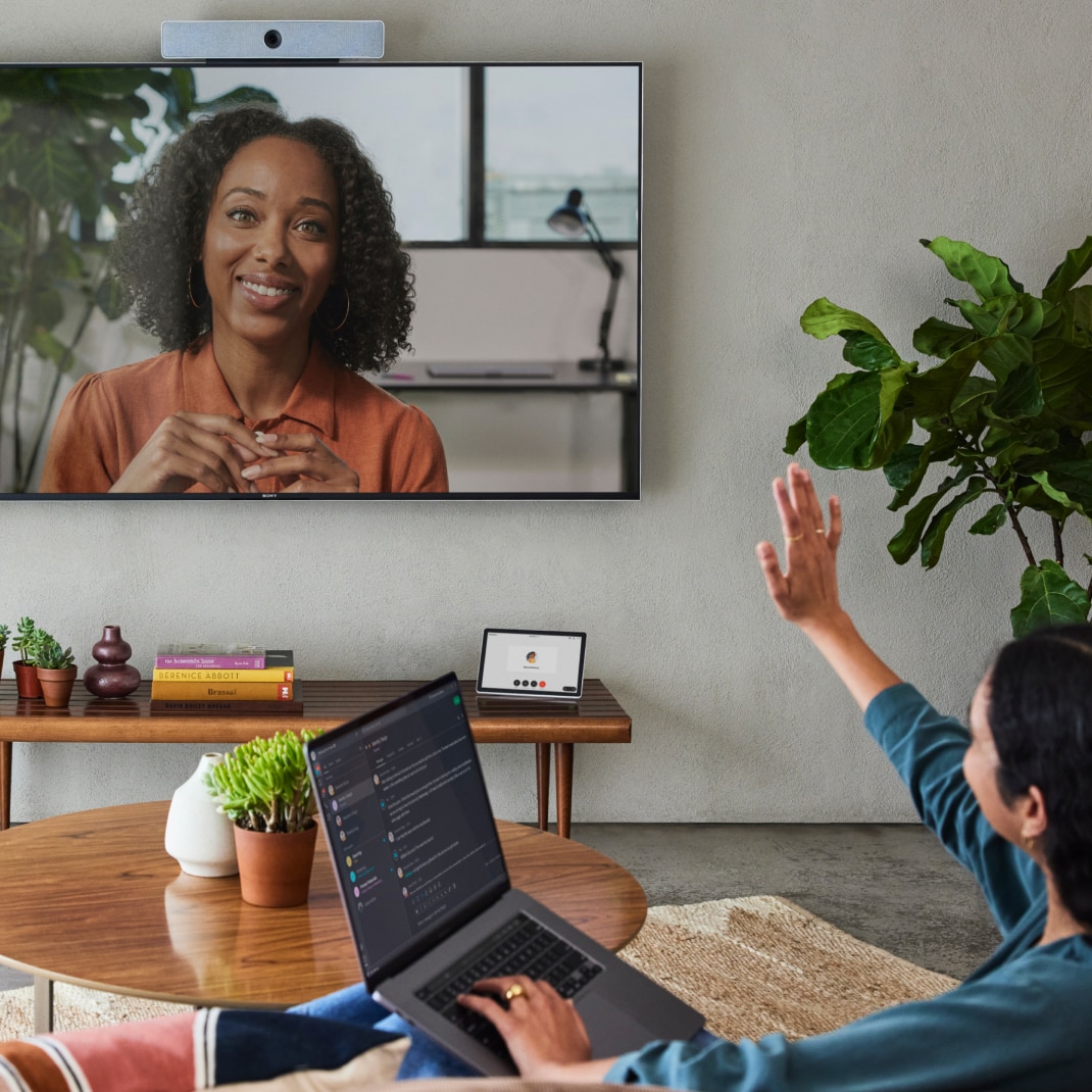 Person video conferences with a colleague via Webex, sharing the meeting to a Webex device from a laptop using Apple AirPlay.
