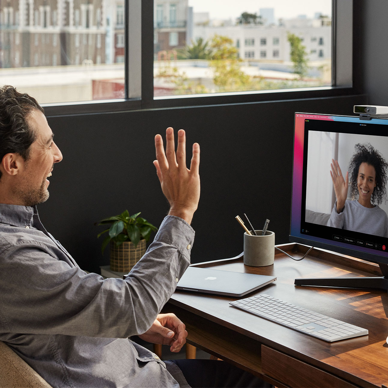 Remote worker waves to his colleague during an online meeting with a Cisco webcam.