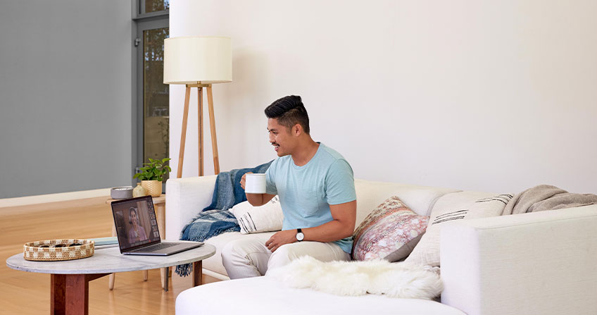 Remote worker attends virtual meeting over coffee while Webex Assistant takes notes.