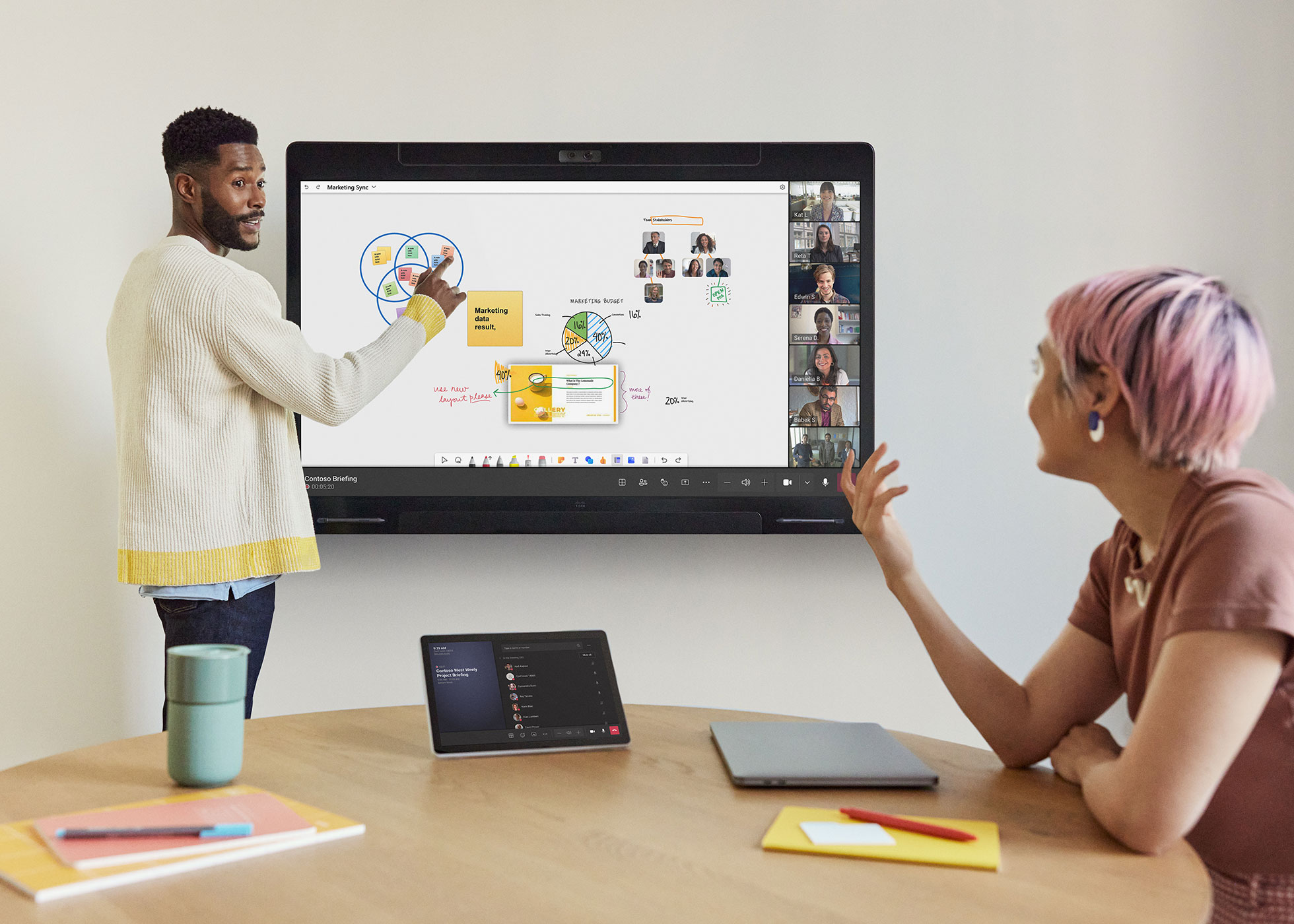 オフィスで Cisco Board Pro を使って Microsoft Teams のリモート参加者とコラボレーションしている同僚 2 人。