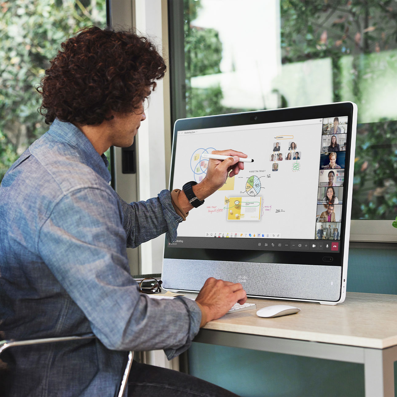 Microsoft Teams を利用して、Cisco Desk Pro でリモート参加者とホワイトボードで作業する従業員。