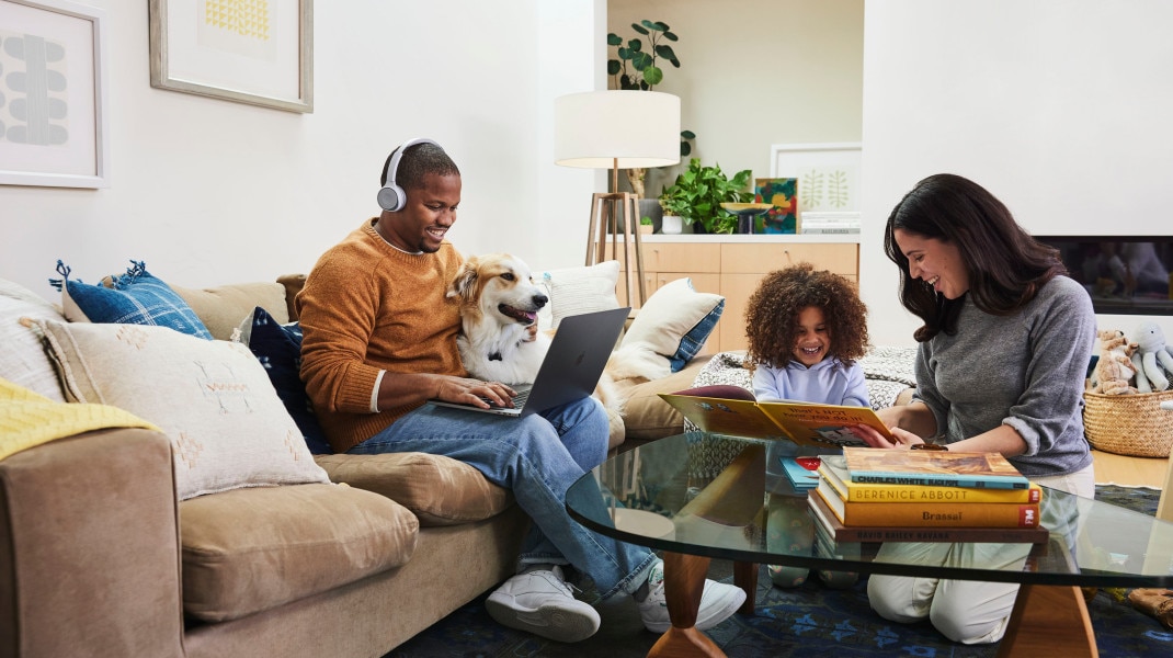 person using laptop and wearing headphones looking happy while sitting with dog