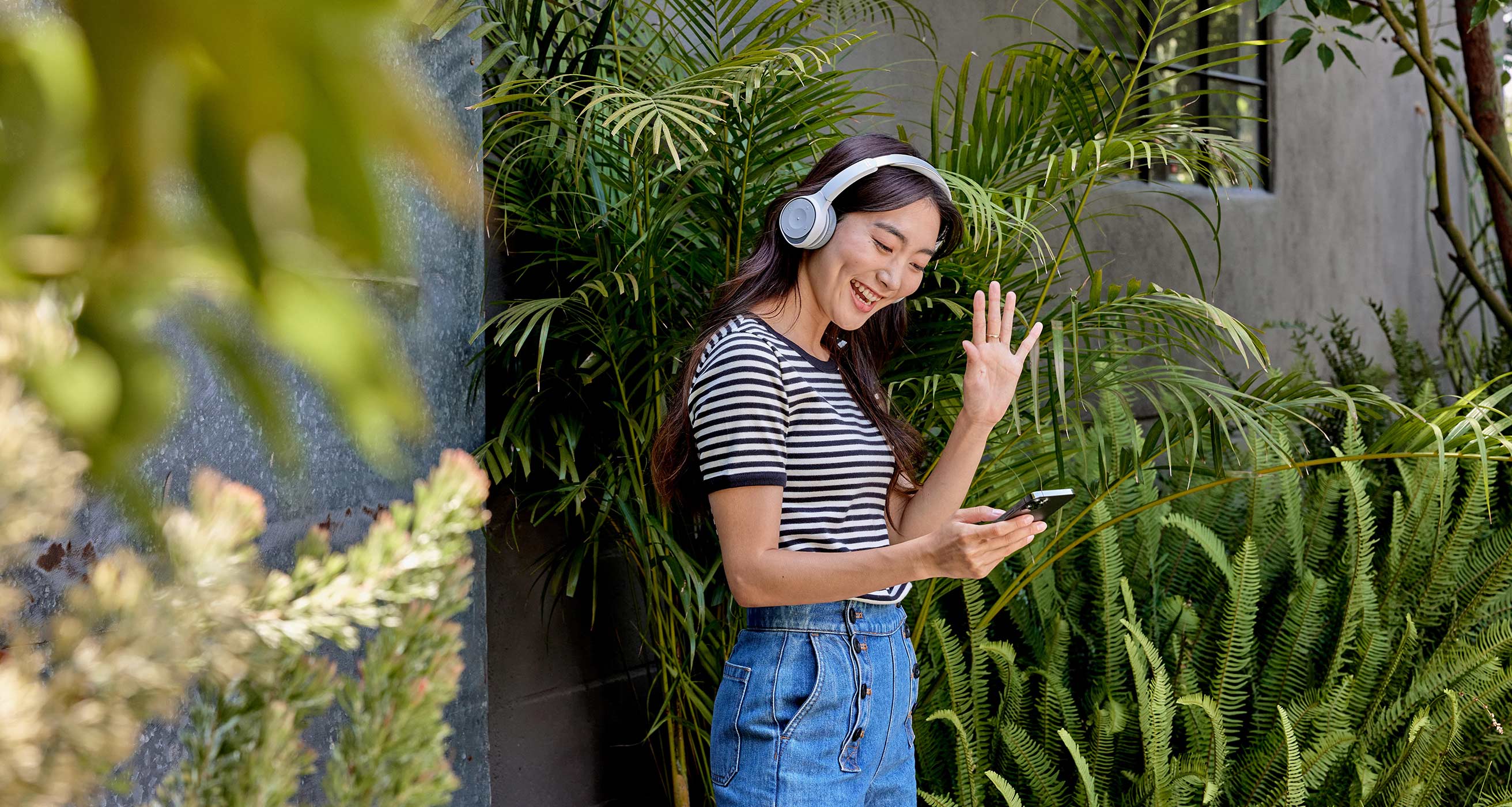 A professional takes a call outdoors on her mobile phone while wearing a Cisco Headset 730.