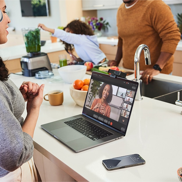 A professional attends a video conference on a laptop with a Cisco Desk Camera mounted to the top.