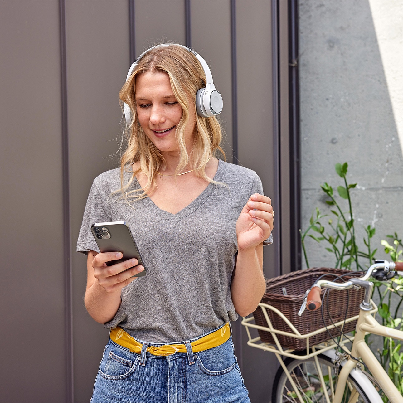 With an iPhone in hand, a professional wearing a Cisco Headset 730 smiles while taking a call outdoors.