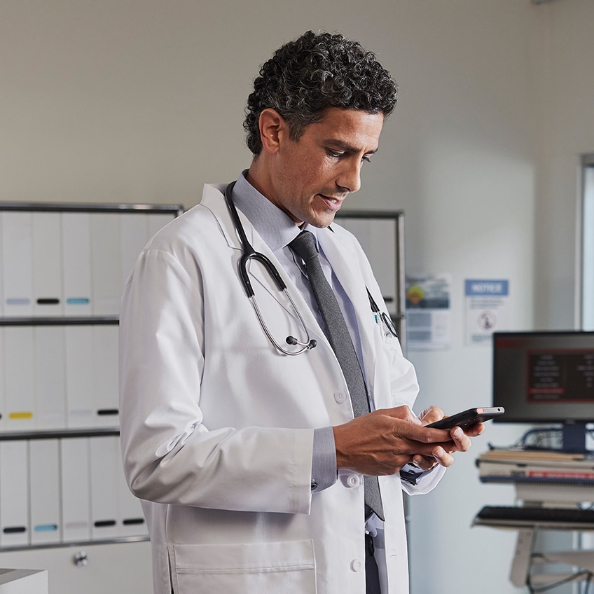 A doctor interacts with his phone while in a medical setting.