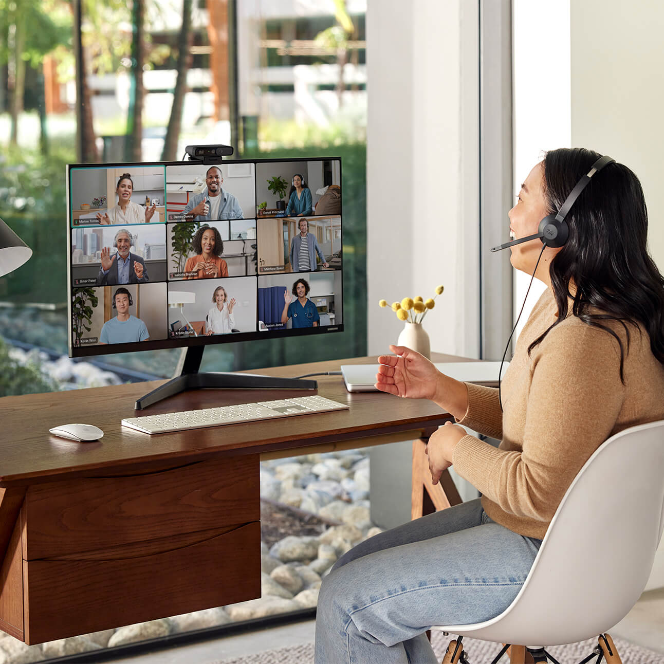 A professional laughs with several colleagues during a video meeting using the Desk Camera 1080p.