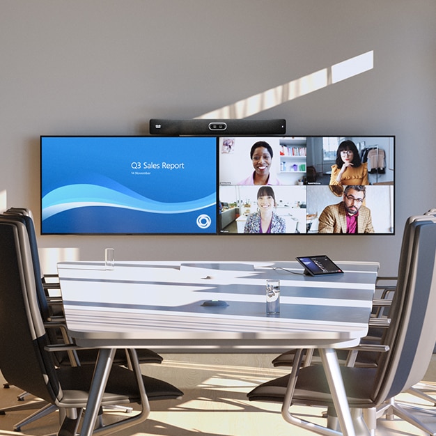 A conference room with the Cisco Room Bar Pro video bar mounted above two screens. A Microsoft Teams Meeting is displayed on the screens.