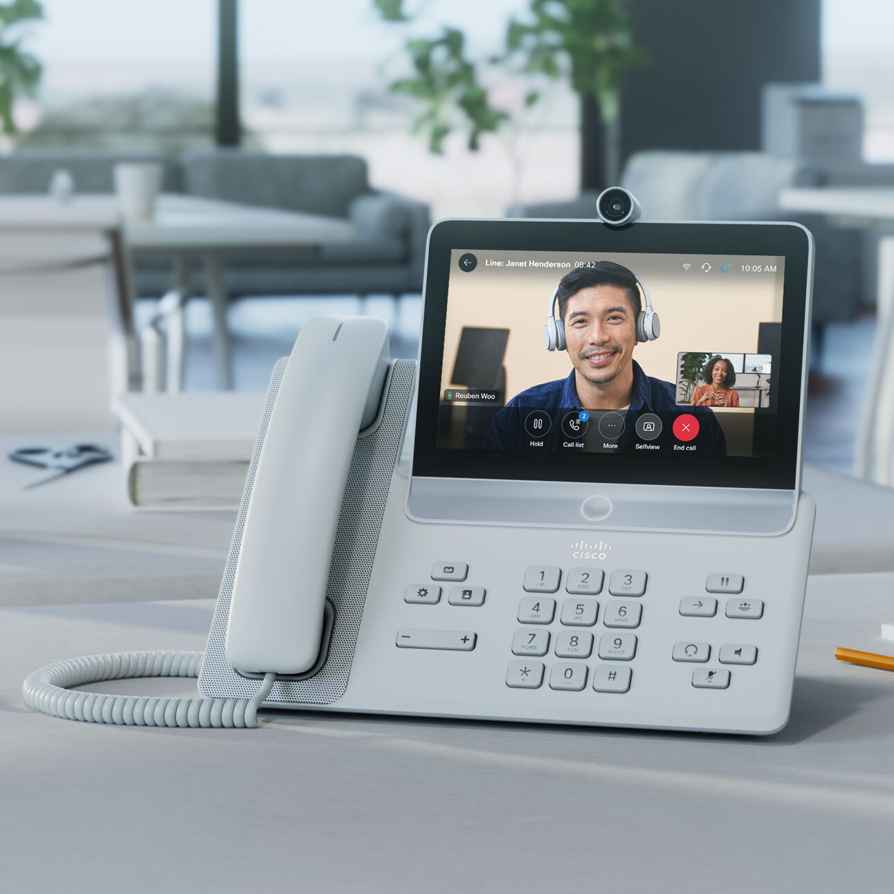 Video meeting in progress on a Cisco Video Phone 8875. Phone's screen shows a colleague who has video conferenced in.