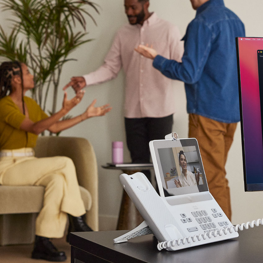 Person takes call from the Cisco Video Phone 8875, using noise removal to avoid background noise from people chatting nearby.