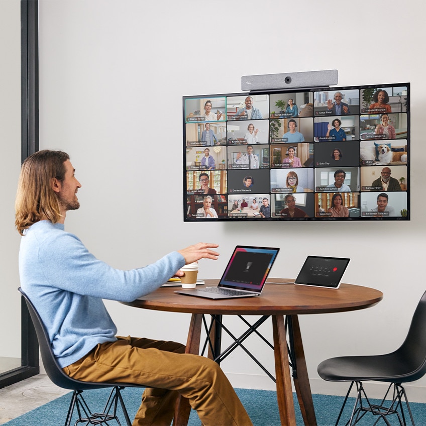 Person in video conference with colleagues, extending his laptop to a 4K display using the Cisco Room Bar video bar and a USB-C passthrough.