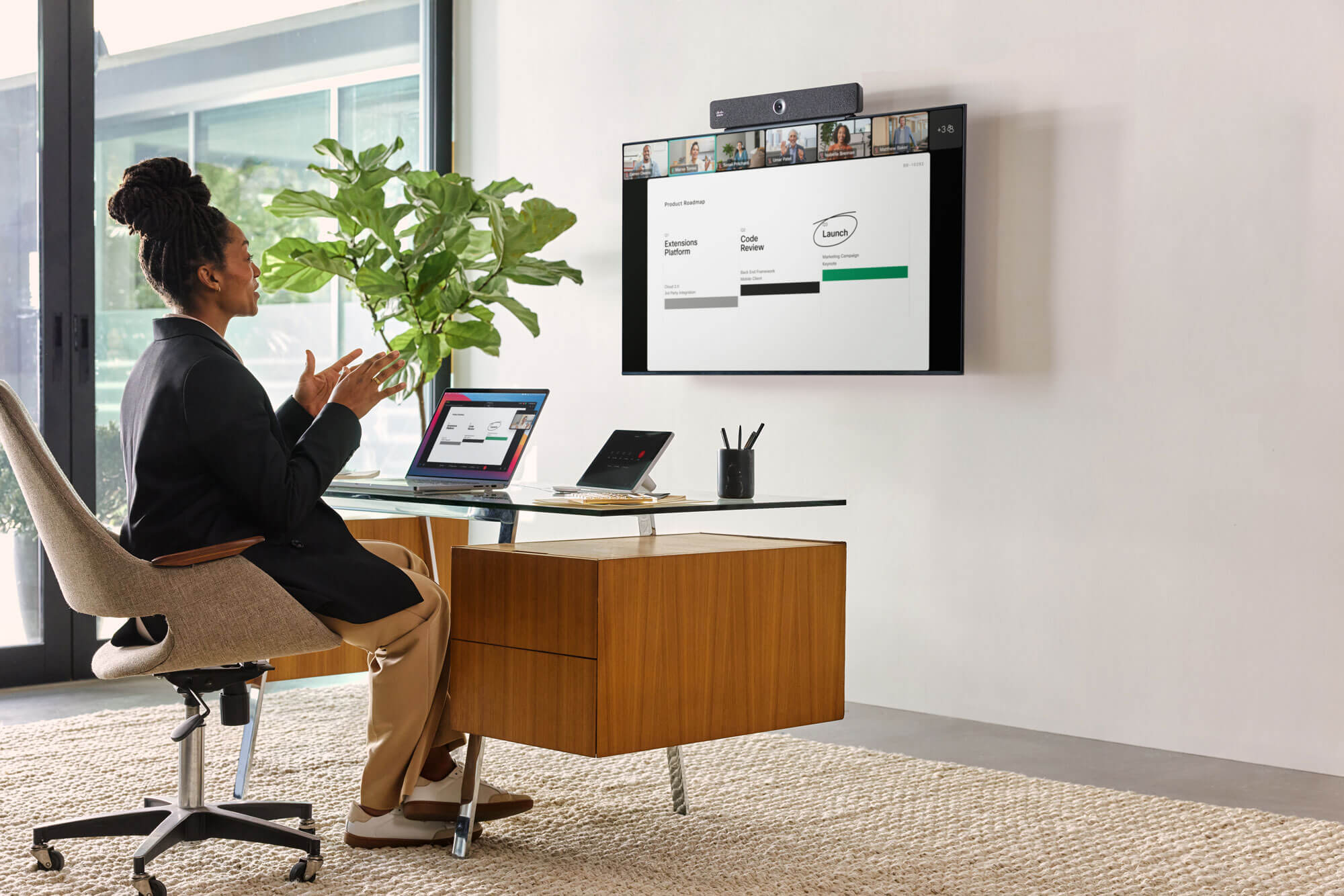 Person video conferences with several colleagues, using the Webex Room Bar. Camera is visible at the device's center.
