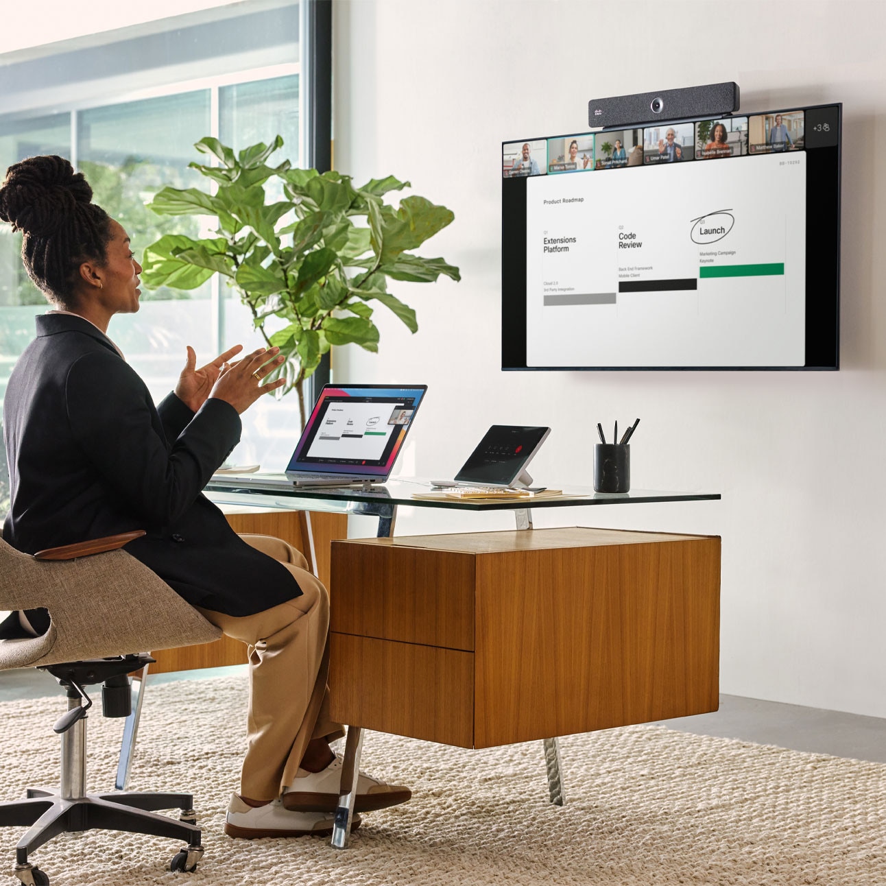 Person in video conference with several colleagues, using the Cisco Room Bar. Camera is visible at the video bar's center.