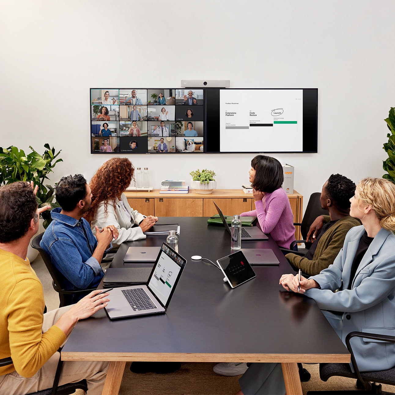 6 colleagues collaborate in a conference room, video conferencing and content sharing with several remote colleagues using the Cisco Room Bar video bar.