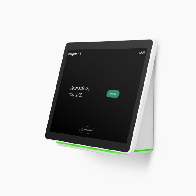 Cisco Room Navigator on wall. Screen shows time of 9:00, a green Book Now button, and notes “Room available until 10:00