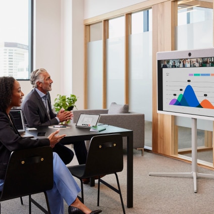 two people in a conference room with a small digital whiteboard holding their attention