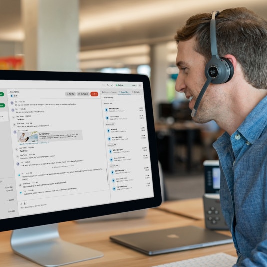 person at desk with headphones on, looking busy or on a call