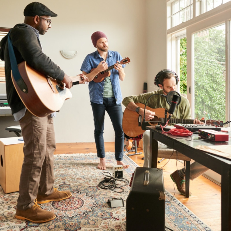 three people playing music around a table