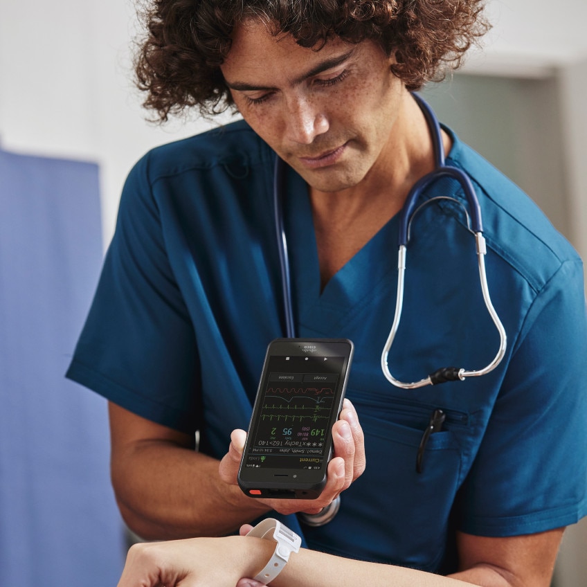 A healthcare professional with a stethoscope around their neck works on a smartphone.