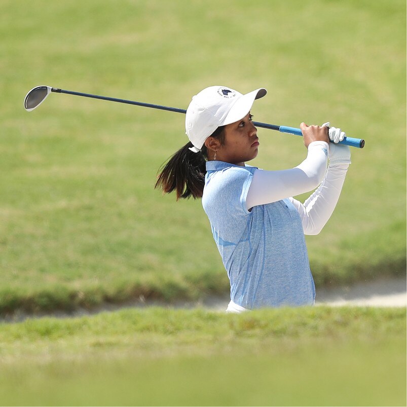 Golfer swings a club on the green.